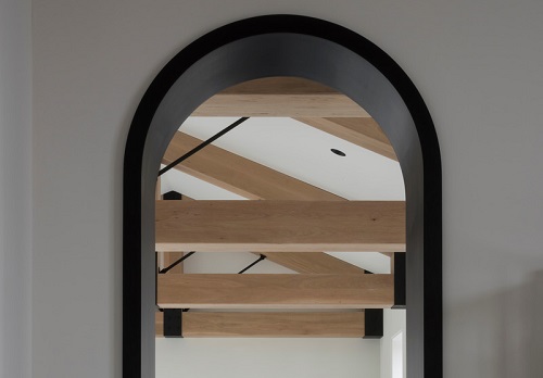 Exposed wooden beams reflecting the original structure’s integrity were maintained, with layers of dark stain and black metal trim added to provide a more industrial feel. Image credit: VSHD
